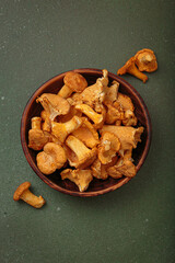 Fresh chanterelle mushrooms in a rustic wooden bowl, on a green background, a warm and inviting autumnal scene perfect for culinary uses