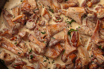 Close up of delicious chanterelle mushrooms frying in a creamy sauce with fresh dill and parsley, close up top view