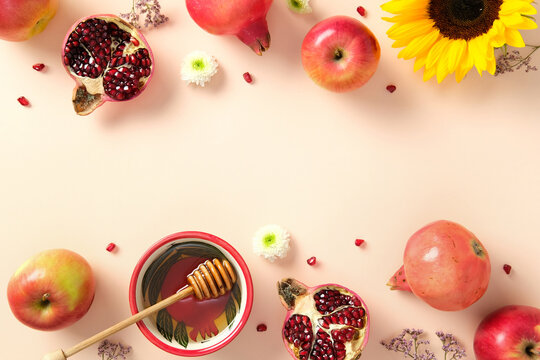 Rosh Hashanah flat lay celebrating Jewish New Year. Apples, pomegranates, honey bowl, and sunflower arranged on light beige background. - Powered by Adobe