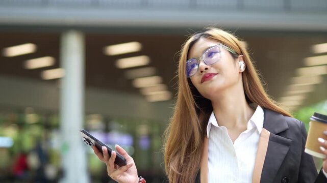 Close-up of Asian businesswoman using mobile phone, texting and cheating on her smartphone while outside office.