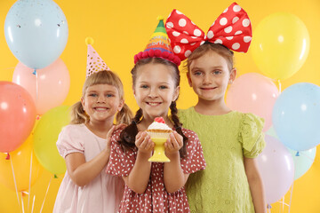 Birthday celebration. Kids with cupcake and balloons on orange background