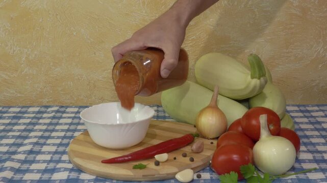 pouring ketchup from a can into a bowl, a man pours tomato sauce into a plate, vegetables zucchini tomatoes and hot peppers