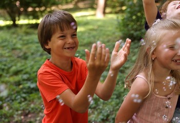 Obraz premium Cute little kids having fun with soap bubbles in park