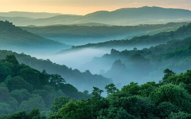 Misty mountain range with green trees and a hazy sky at early morning