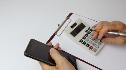 Fototapeta premium Notepad with blank sheet of paper, copy space, and a man's hand using a calculator