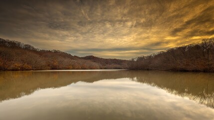 Fototapeta premium A serene lake mirroring golden sunset and forest, creating a perfectly symmetrical dreamscape.