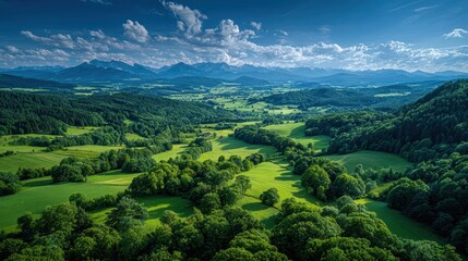 Obraz premium Scenic Aerial View of Lush Green Valley with Mountains and Blue Sky