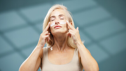 Woman applying skincare treatment with under-eye patches, enjoying a moment of relaxation in a serene spa environment, emphasizing self-care and wellness practices for rejuvenation and beauty