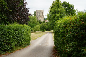 Fototapeta premium Thurgarton, Nottinghamshire, England - August 18 2025: Picturesque country lane leading to historic parish church in summer