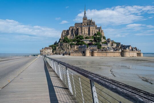Pedestrian bridge leading to Mont Saint Michel Abbey in Normandy France during low tide