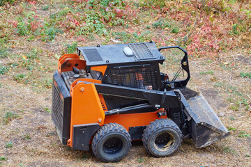 Mini-loader with an open door and a driver inside, mini-loader clearing the area for construction, preparation for building.