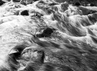 Rushing river water over rocks in black and white