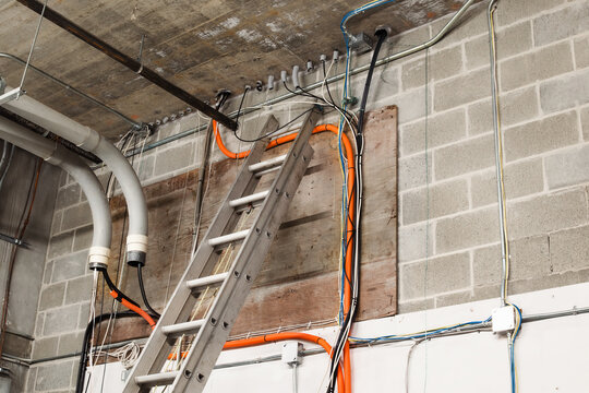 Fiber optic installation for building. Utility or electrical room with many cables and conduits with strings to pull cable. High-speed internet upgrade or telecom infrastructure. Selective focus.