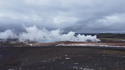 Spectacular aerial drone footage soaring above the geothermal area near Lake Mývatn, North Iceland. Captures powerful steam vents (fumaroles) hissing and swirling over colorful, mineral-rich earth. - Powered by Adobe