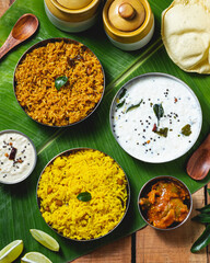 Authentic South Indian meal served on a banana leaf with a variety of dishes including lemon rice, tamarind rice, curd rice, papad, pickle, and coconut chutney. 