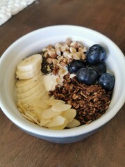 Overhead shot of a wholesome breakfast yogurt bowl filled with blueberries, banana slices, granola, nuts, and chia seeds