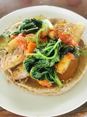 A gourmet plate of perfectly cooked fish served with roasted potatoes, fresh spinach, and a rich tomato sauce, garnished with dill