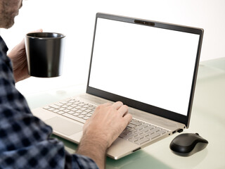 A person working on a laptop while drinking coffee. The computer screen is transparent.