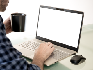 A person working on a laptop while drinking coffee. The computer screen is transparent.
