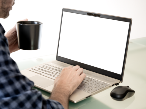 A person working on a laptop while drinking coffee. The computer screen is transparent.