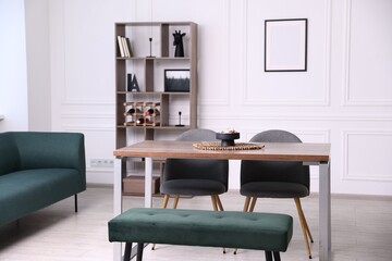 Wooden table with chairs, bench and decor in dining room. Interior design