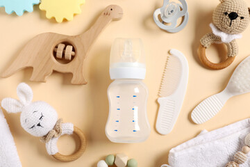 Bottle with milk and baby accessories on beige background, flat lay