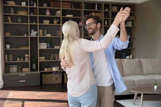 Celebrating home party. Happy older woman waltz in slow dance with adult son grandson in modern designed living room after relocating to new apartment completing interior renovation buying furniture