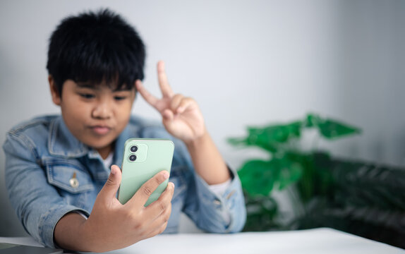 Youth lifestyle, self expression, digital communication, and the global impact of mobile technology and social media. Young person posing for a selfie with smartphone and peace sign.
