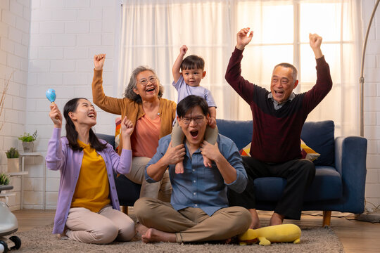 A happy ASEAN family living together as a big family is together in the living room at home, and behind is a sofa.