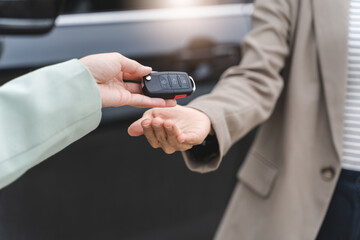 transportation rental automotive business concept. Close up hands of rental auto agent giving car remote key to client to travel sightseeing.
