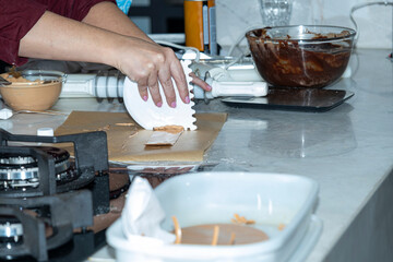 Chef using a spatula to make a caramel chocolate decoration.