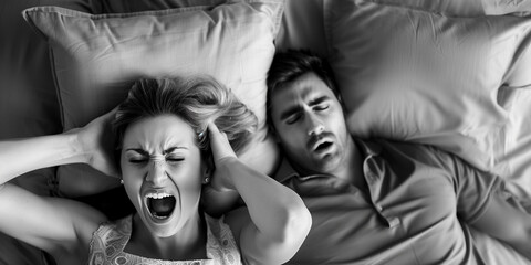 A woman covers her ears and shouts in frustration while her male partner sleeps soundly and snores loudly next to her in bed