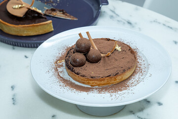 Chocolate pie covered with cocoa powder circular truffles and caramel chocolate.