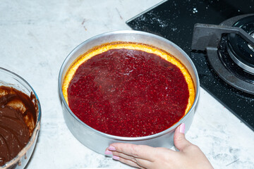 Cheesecake with red fruit topping on a marble countertop.