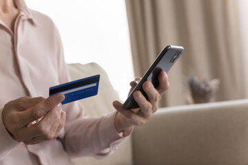 Digital inclusion in older age. Cropped close up elderly female hands hold smartphone credit bank card. Fraud awareness online purchases web banking internet transactions mobile payment safety concept