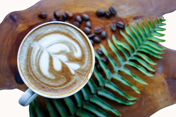 coffee mug cappuccino and roasted coffe beans with green leave on wooden table background top view