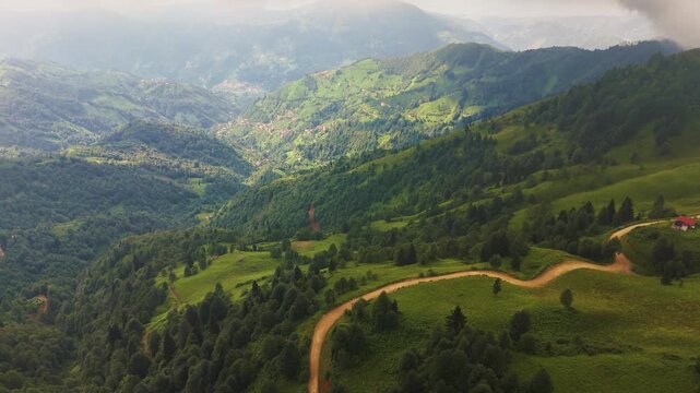 Breathtaking aerial view of a winding dirt road amidst lush green valleys and rolling hills in the Black Sea region of Turkiye