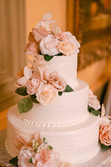Elegant three-tier wedding cake adorned with pastel flowers at a lovely reception