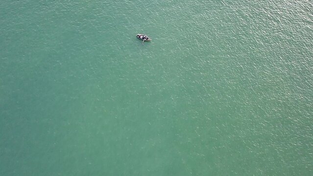 Aerial drone top-down view of a small boat with people sailing on the serene green waters of the Historic Center of Recife, Pernambuco, Brazil. Minimalist and vast ocean scape. - Powered by Adobe