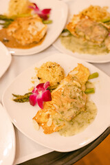 Salmon fillet garnished with herbs served with asparagus and rice in a restaurant setting during an evening event