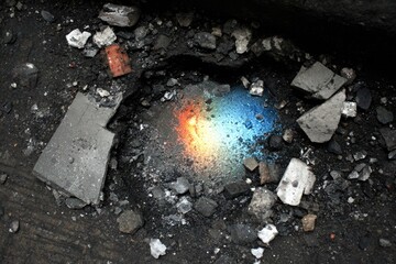 A hole in dark ground, fire reflects rainbow colors