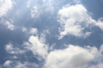 Fototapeta premium Bright blue sky with soft, fluffy white clouds drifting peacefully, creating a serene and refreshing view of nature’s beauty. Suitable for nature and simple background.