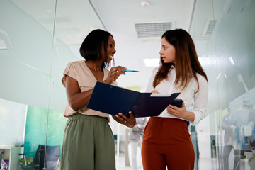 Obraz premium Two business people reviewing documents and discussing in a modern office