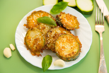 Crispy zucchini slices in sesame on a white plate