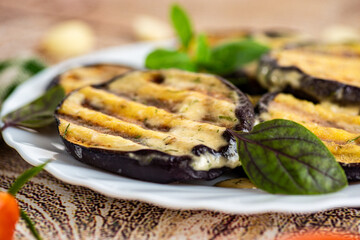 Juicy eggplant slices on a white plate, rustic serving