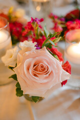 Elegant floral arrangement featuring pink and red roses with soft candlelight ambiance at a special event