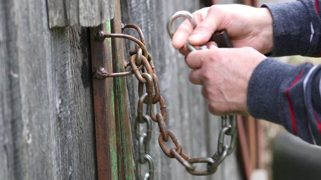 A close-up of a rusty padlock secured on a weathered wooden door. 