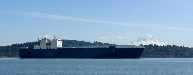 A large, black container ship transits Commencement Bay on its way to the Port of Tacoma with beautiful Mount Rainier gracing the skyline in the background.