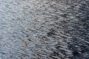 The texture of the lake's water surface, with small ripples, small waves and reflections on an overcast day.
