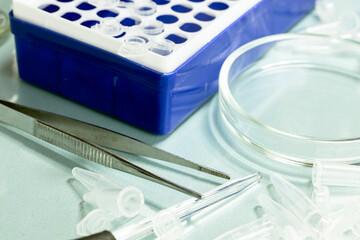 Laboratory equipment including test tubes, pipettes, and tweezers on a work surface. 